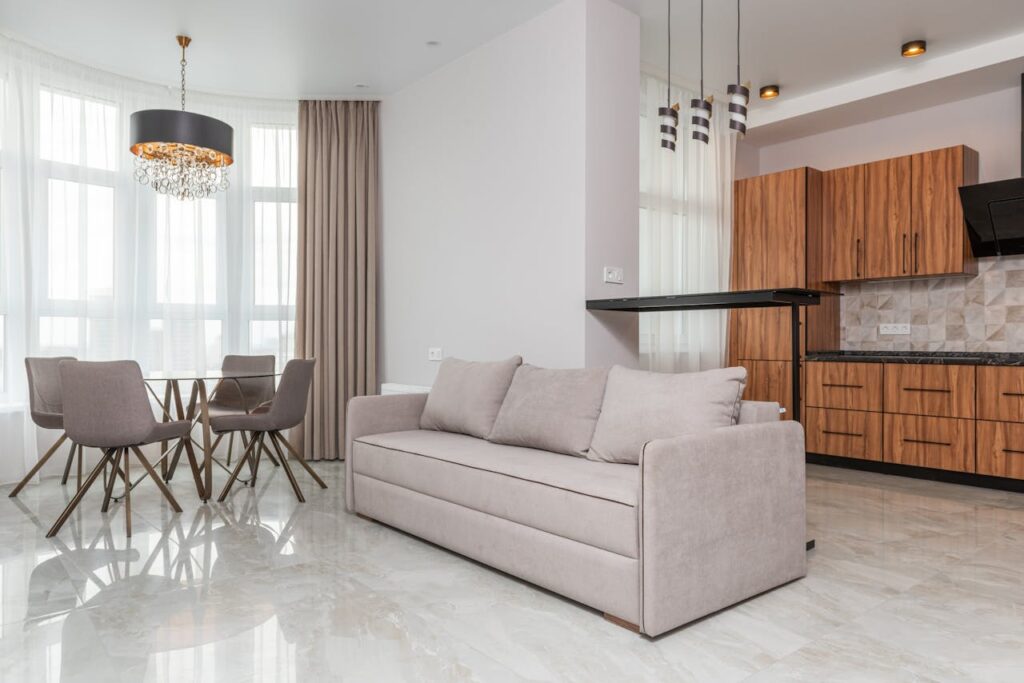 pexels-photo-6436790 Interior of modern flat with kitchen counter with wooden cabinets placed near sofa bar counter and table with chairs at home